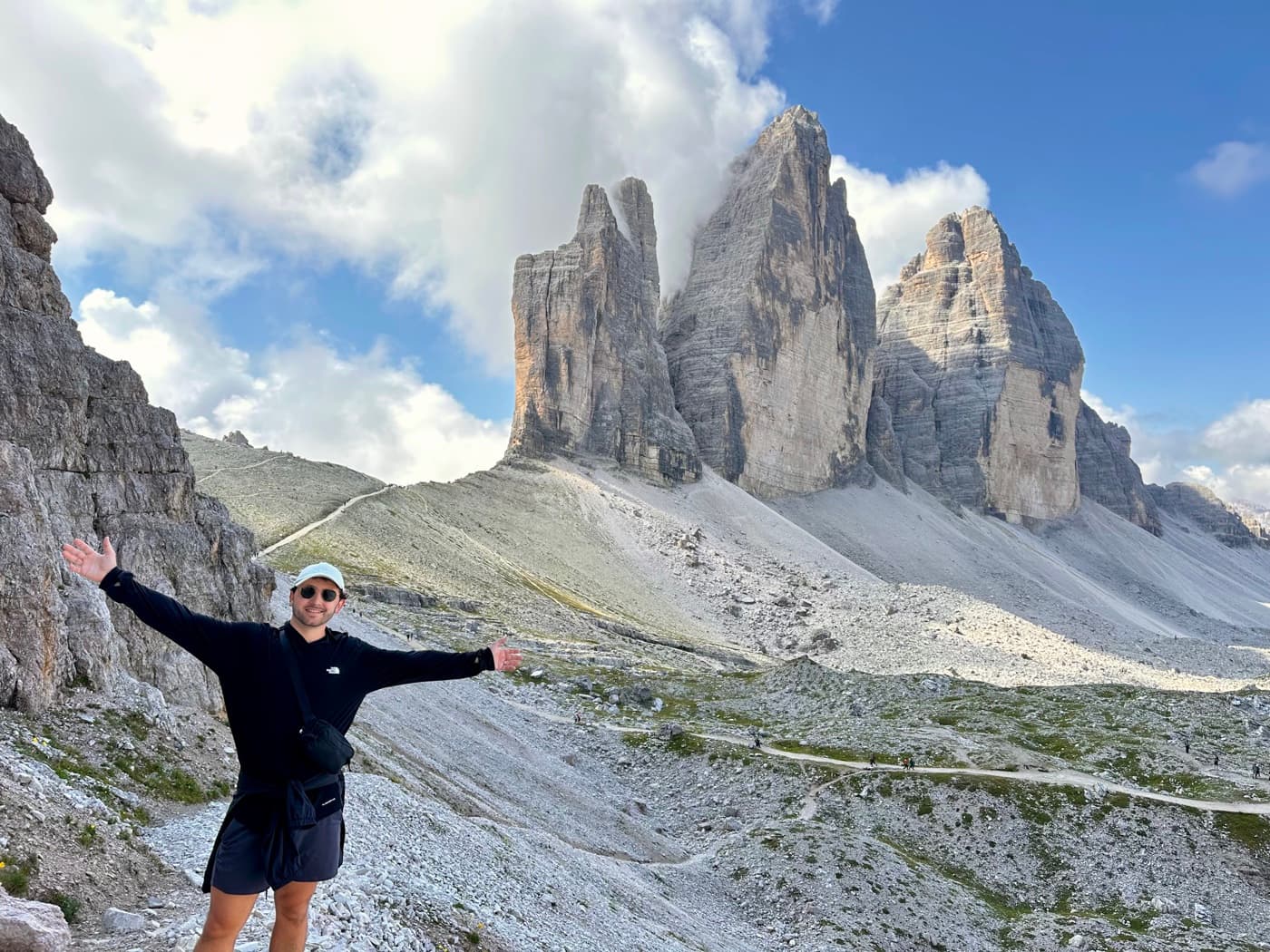 Dylan with arms out on the trail below the Tre Cime di Lavaredo in the Dolomites